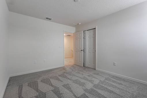 A room with a carpeted floor and a doorway leading to another room.
