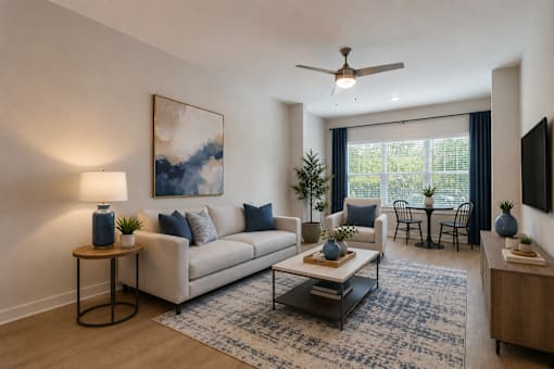 Thoughtfully designed living room at Blue Sky Landing featuring an open-concept layout, modern furnishings, wood-style flooring, and large windows in a pet-friendly one-, two-, and three-bedroom apartment community in College Park, GA.