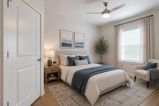 Bright guest bedroom at Blue Sky Landing featuring a spacious layout, ceiling fan, plush carpeting, and natural light in a thoughtfully designed apartment home in College Park, GA.