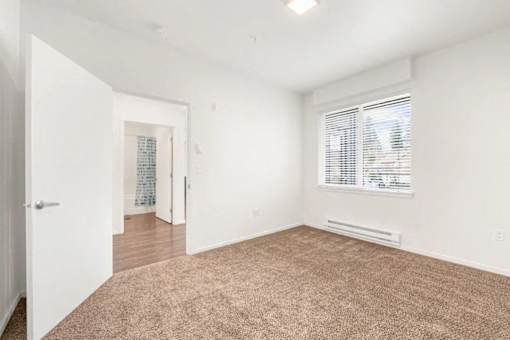 A room with a carpeted floor and a window with blinds.