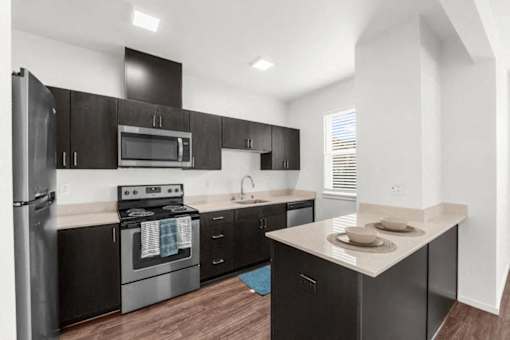 A kitchen with black cabinets and stainless steel appliances.