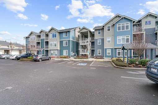 A parking lot in front of a row of apartment buildings.