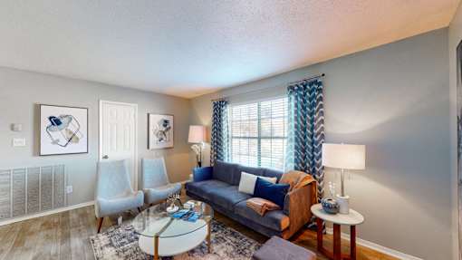 Living room at Broad on the Green in Augusta, GA, featuring a large window, Wood-Vinyl Plank Flooring, and bright natural light in a pet-friendly apartment community.