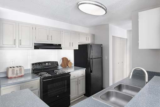 A kitchen with black appliances and white cabinets.