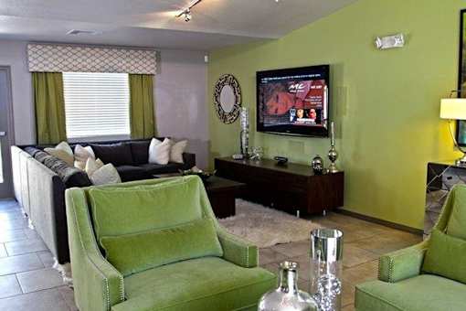 A living room with a green chair and a black couch.