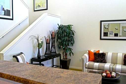 A living room with a couch, a table with a vase and a plant on it, and a staircase in the background.