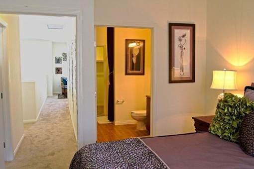 A bedroom with a bed, lamp, and a painting on the wall.