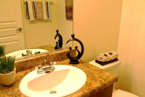 A bathroom with a sink, toilet, and a mirror.