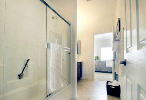 A bathroom with a glass shower door and a black bag on the floor.