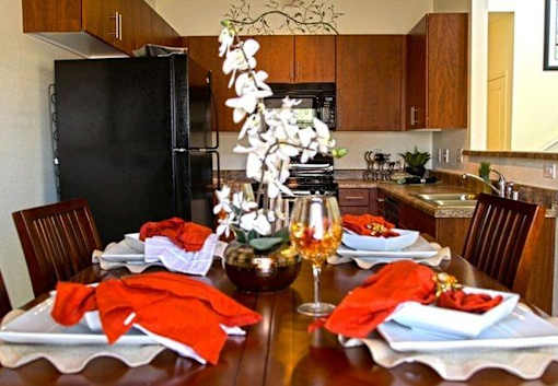 A dining table set for a meal with a vase of flowers in the center.