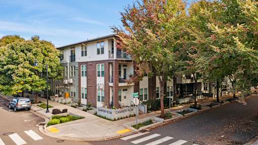 A street view of a residential area with apartment buildings and trees.