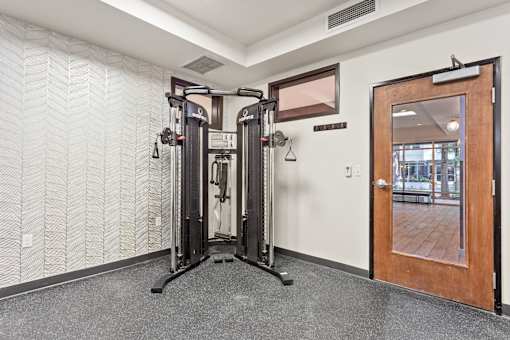 A gym room with a squat rack and a mirror.