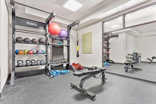 A gym with a variety of equipment including weights and a bench.