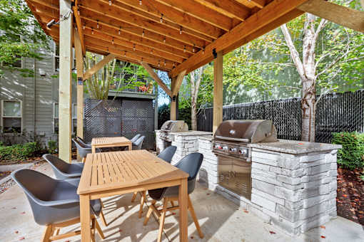 A wooden table and chairs are set up under a wooden pergola.