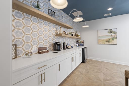 Pet-Friendly Apartments in Savannah, GA – The Palms at Chatham – a kitchen with white cabinets and blue tiles on the wall from our clubhouse