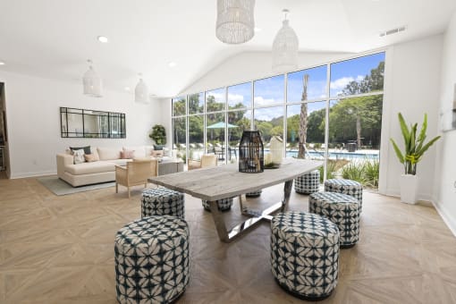 Apartments in Savannah, GA for Rent – The Palms at Chatham- our clubhouse with a large wooden table and stools in front of a large window