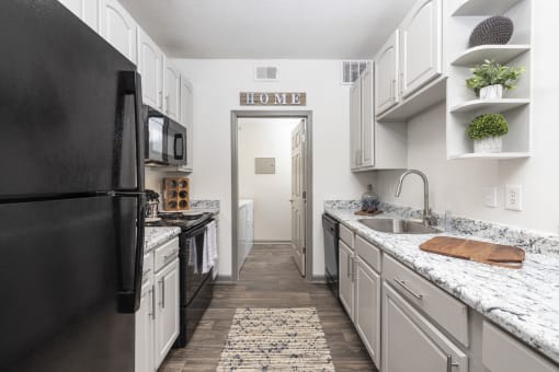 Savannah, GA Apartments – The Palms at Chatham– a kitchen with white cabinets and black appliances