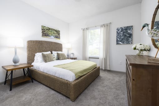 Savannah, GA Apartments – The Palms at Chatham– a bedroom with a large bed and a dresser with a lamp