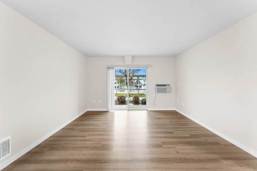 A large empty room with wooden floors and white walls.