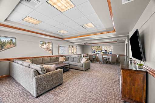 A spacious living room with a grey sofa set and a television.