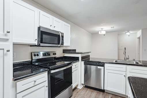 Apartments for Rent in Little Rock, AR 72223– Capitol Hill -   A kitchen with white cabinets and black countertops.