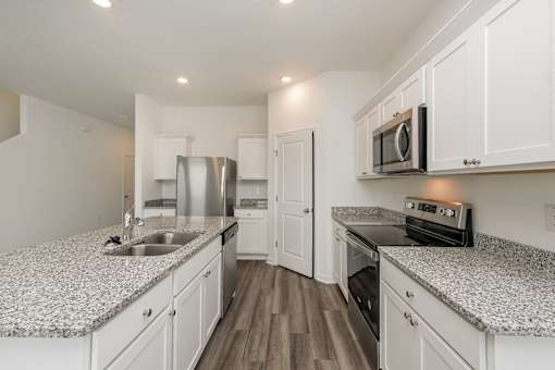 Ruskin, FL Homes - Ruskin Reserve Luxury Kitchen with white cabinets wooden floors granite countertops