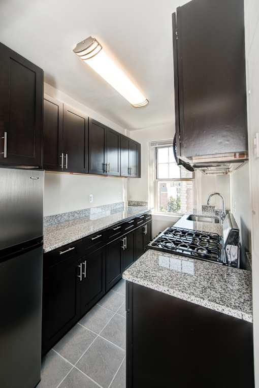 A kitchen with black cabinets and a granite countertop.