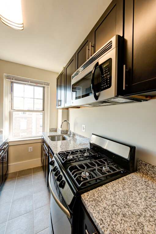 A kitchen with black cabinets and a black stove top.