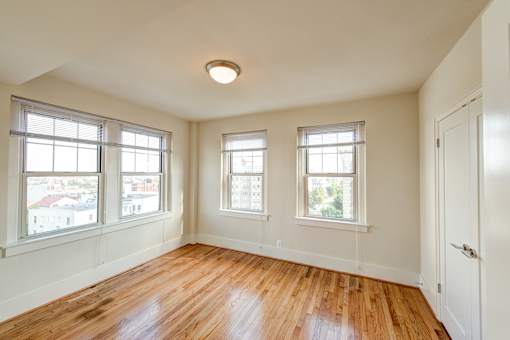 A room with wooden floors and three windows.