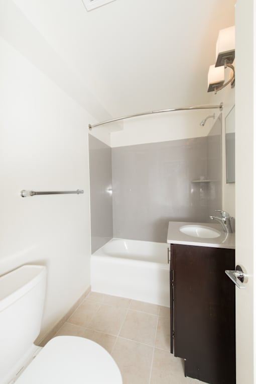 A white toilet sits next to a white bathtub in a small bathroom.