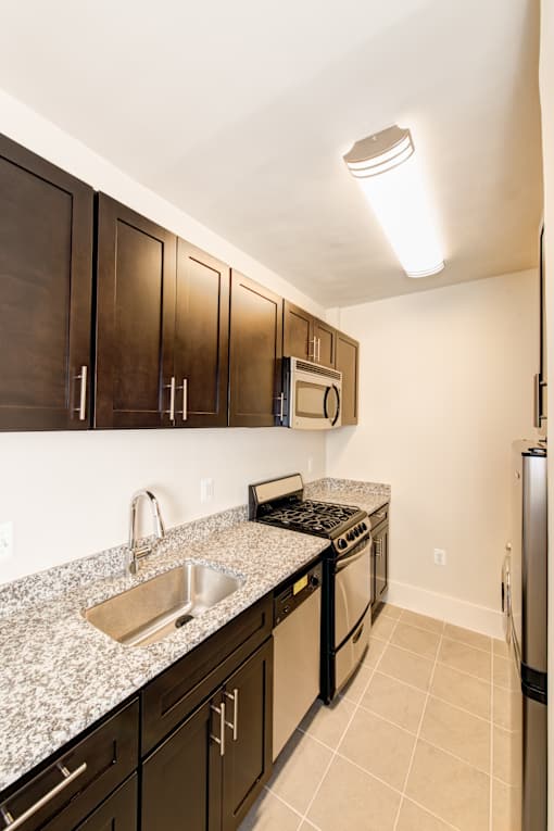 A kitchen with brown cabinets and a granite counter top.