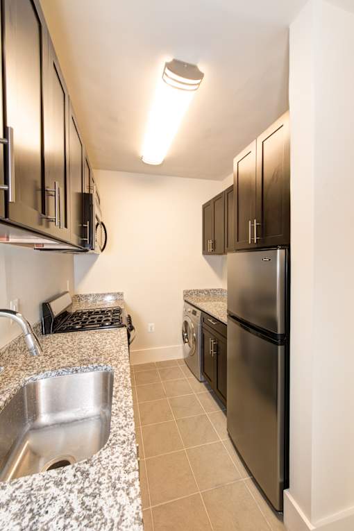 A kitchen with a sink, refrigerator, and cabinets.