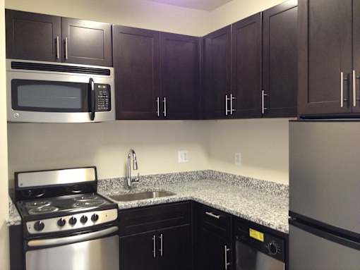 A kitchen with a stove, microwave, and refrigerator.