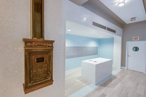 A white box sits on a wooden floor in a room with a letter box on the wall.