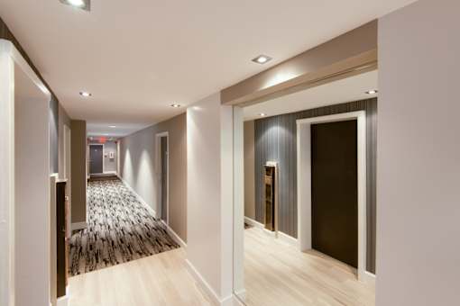 A hallway with a carpeted floor and wooden flooring.