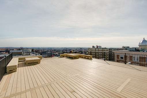 A wooden deck with benches overlooks a cityscape.