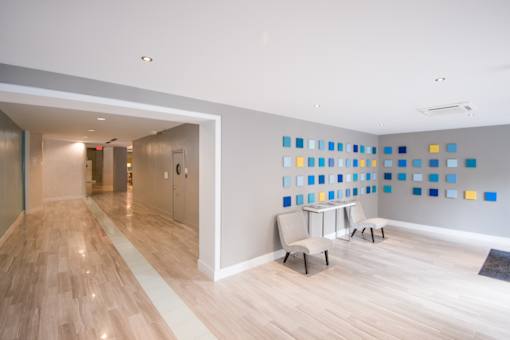 A hallway with a blue and yellow wall and two chairs.
