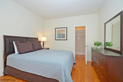 A bedroom with a bed, nightstand, and a painting on the wall.
