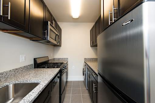 A kitchen with black cabinets and stainless steel appliances.
