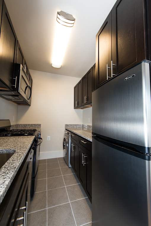 A kitchen with a stainless steel refrigerator and black cabinets.