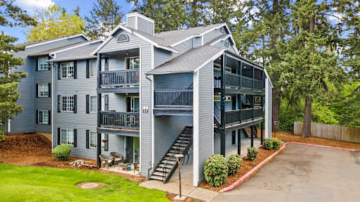 A grey two story apartment building with a balcony on the second floor.