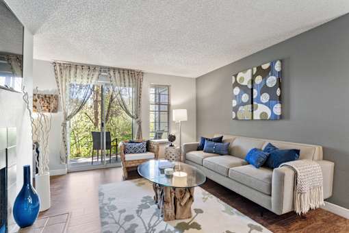 A living room with a couch, coffee table, and a large window with curtains.