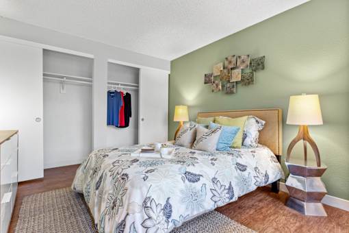 A bedroom with a large bed and a lamp on a side table.
