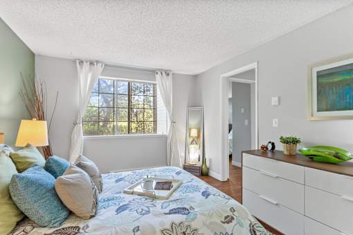 A bedroom with a bed, nightstand, and window.
