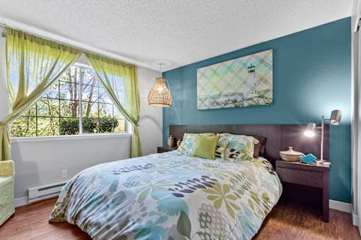 A bedroom with a bed, nightstand, and window with curtains.