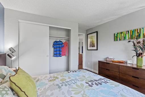A bedroom with a bed, dresser, and a painting on the wall.