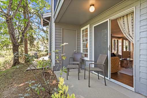 A patio with chairs and a table is on the front porch of a house.