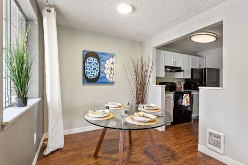 A dining room with a glass table set for two.