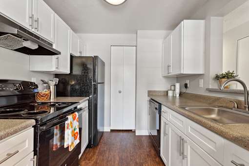 A kitchen with black appliances and white cabinets.