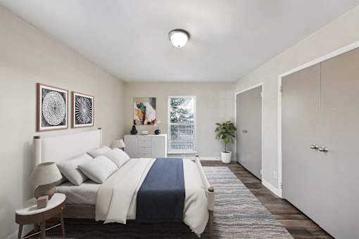 Apartments in Sandy Springs Georgia for Rent – Celebration at Sandy Springs - A bedroom with a bed, nightstand, and a plant.
